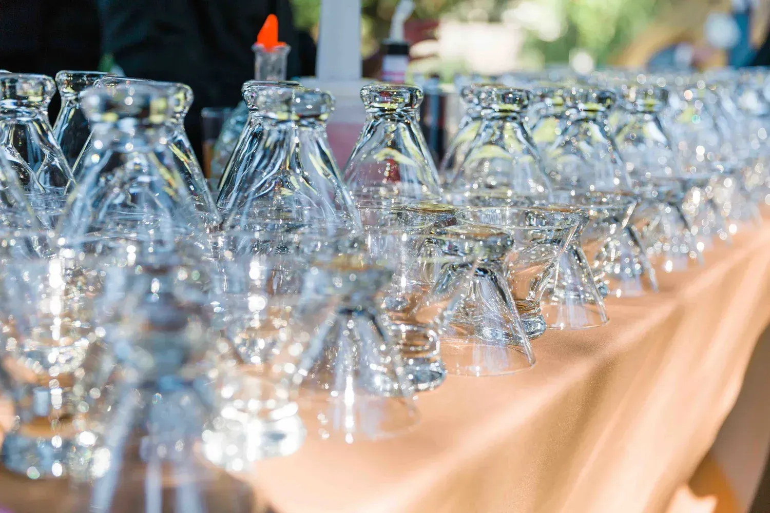 Rows of upside-down wine glasses on a table, with one orange marker among them