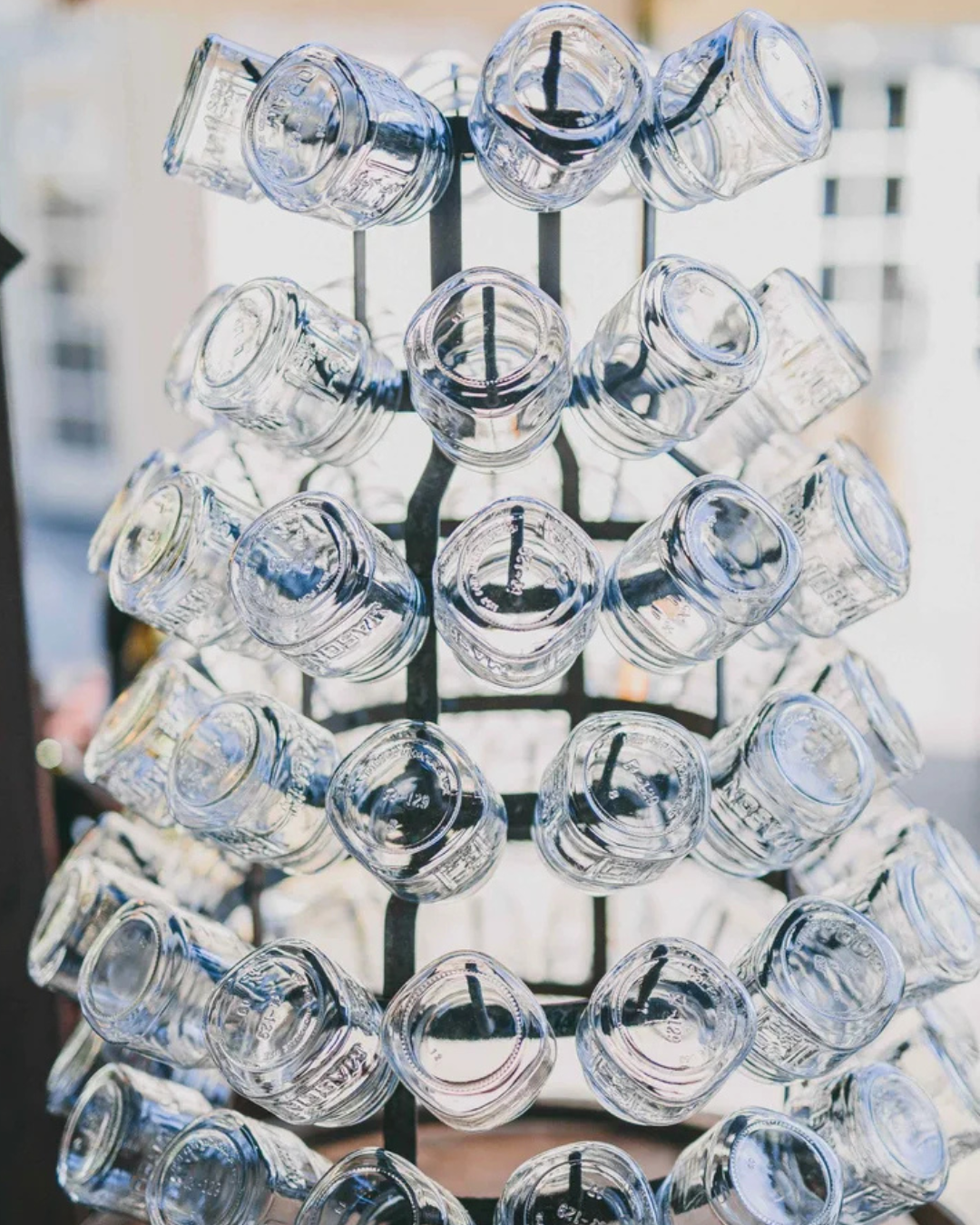 Stacked clear glass jars arranged on metal racks, viewed from the front