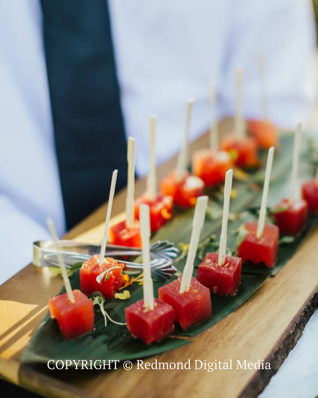 Skewered watermelon and strawberry appetizers arranged on a serving board at an outdoor event