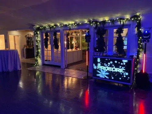 Festive indoor booth with blue lights, garlands, and a glowing sign on a polished floor