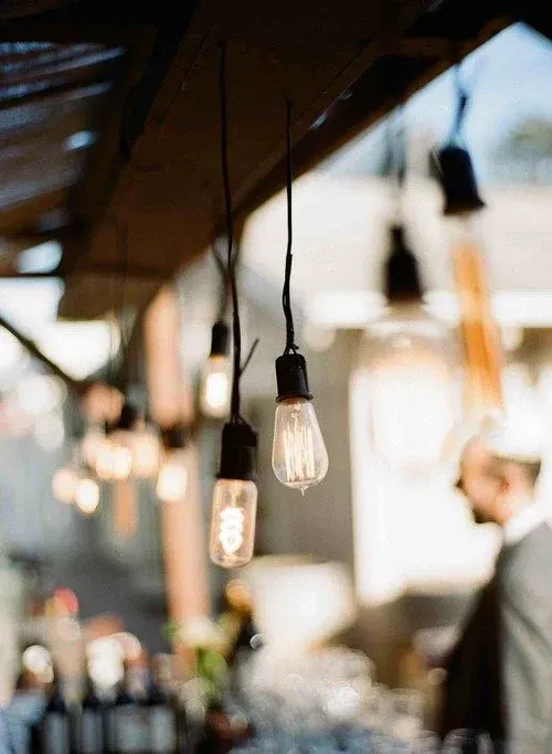 Hanging Edison-style bulbs in a warm, blurred cafe or bar interior with people in the background