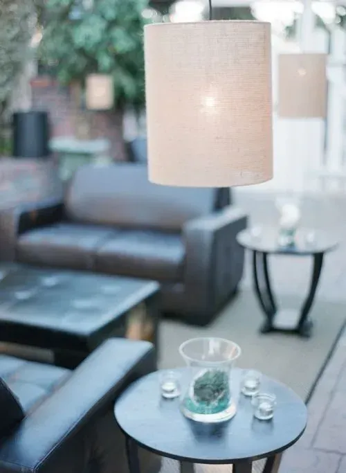 Modern patio seating area with gray sofas, round black tables, and hanging lamps