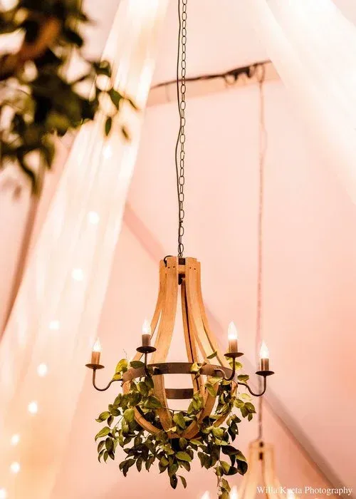 Chandelier with candles and greenery hanging in a soft pink tented space