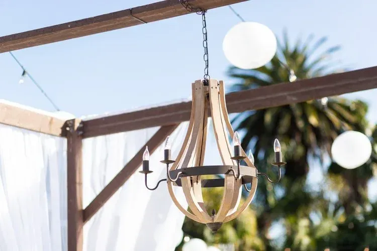 Wooden hanging lantern light fixture on a pergola with round string lights in the background