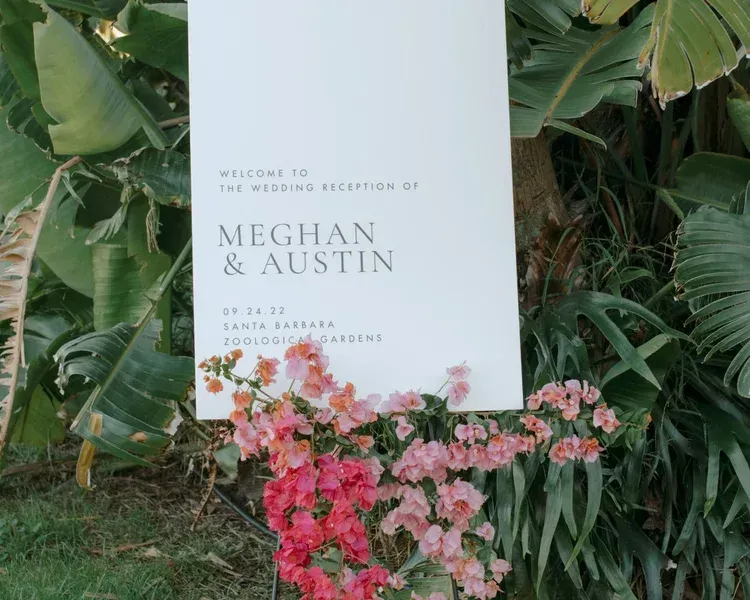 Wedding welcome sign with pink flowers and lush greenery backdrop