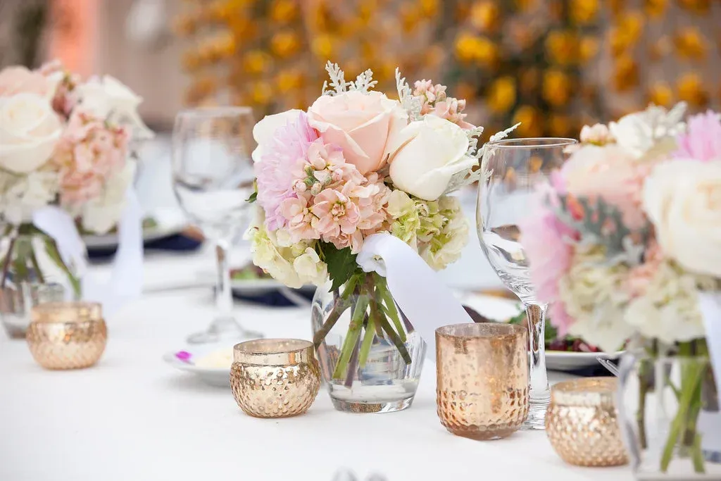 Elegant table setting with pink-and-white floral centerpieces and glowing votive candles