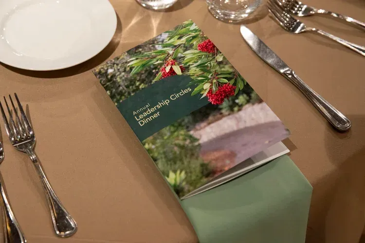 Holiday menu card on a tan table setting with plates, silverware, and wine glasses