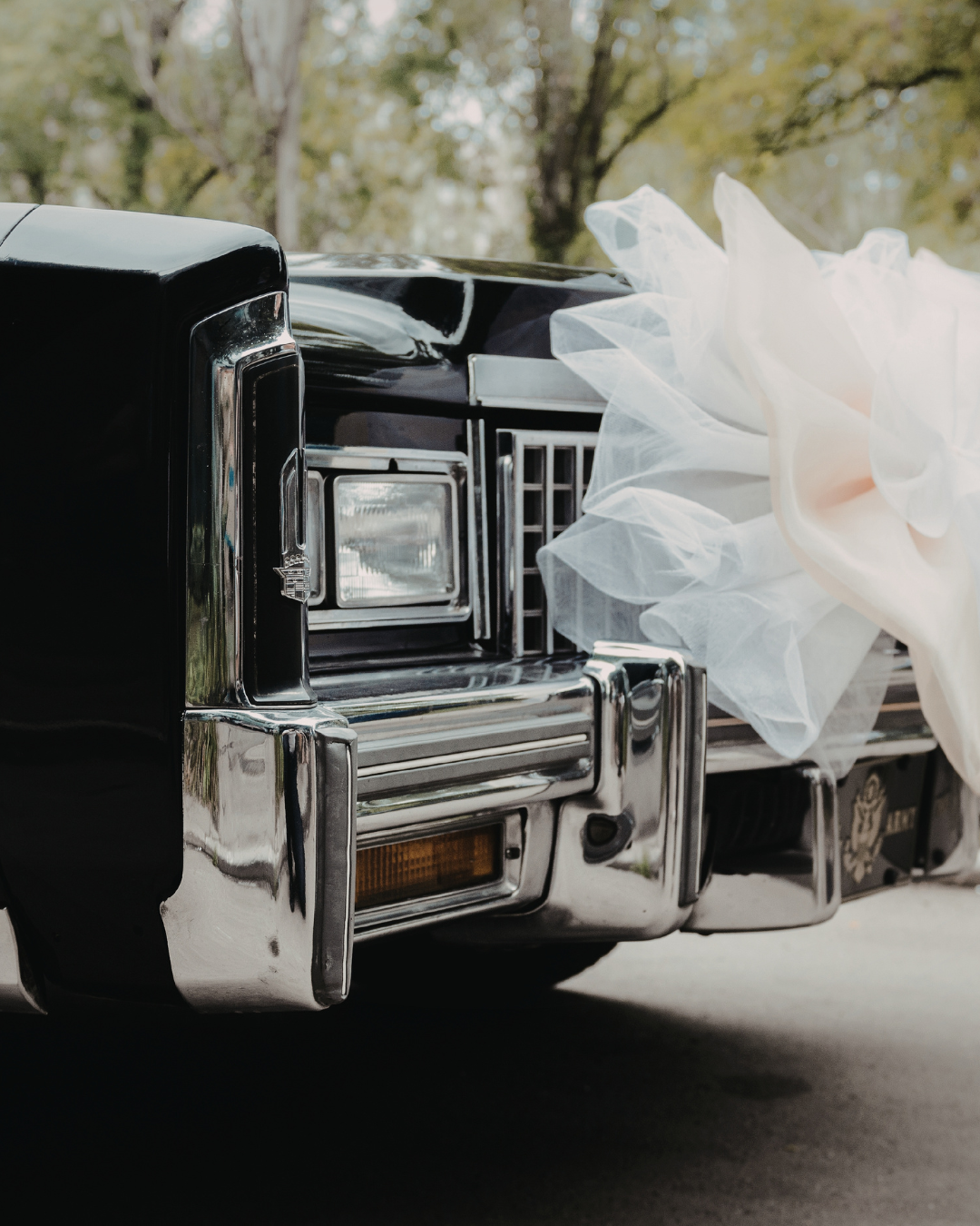 Chrome car front with a white ribbon bow attached, outdoors