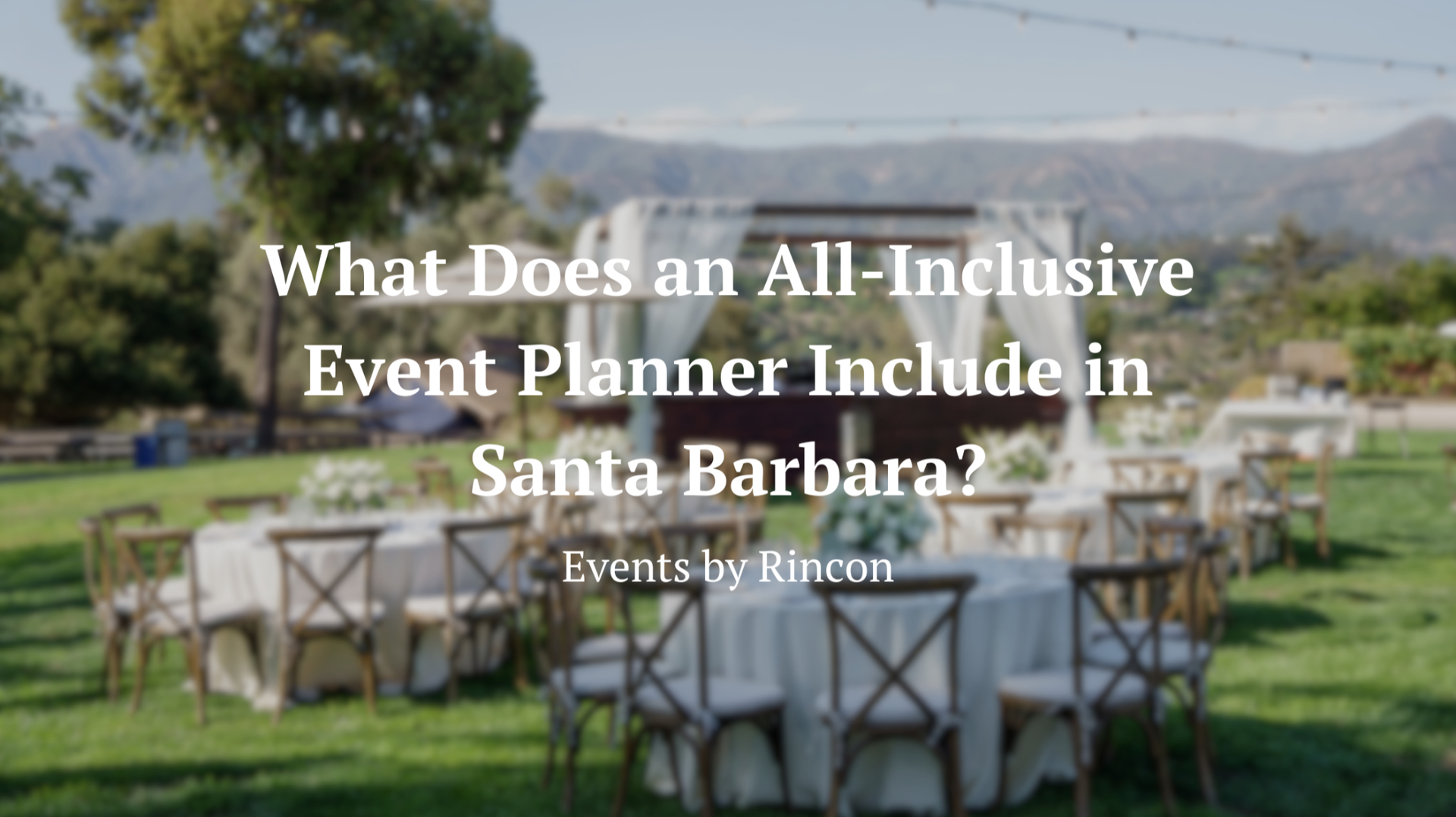 Outdoor wedding reception setup with white chairs and tables under string lights in a grassy mountain venue