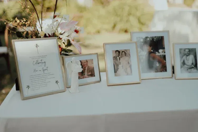 Wedding display table with framed photos and a flower arrangement in soft, warm light