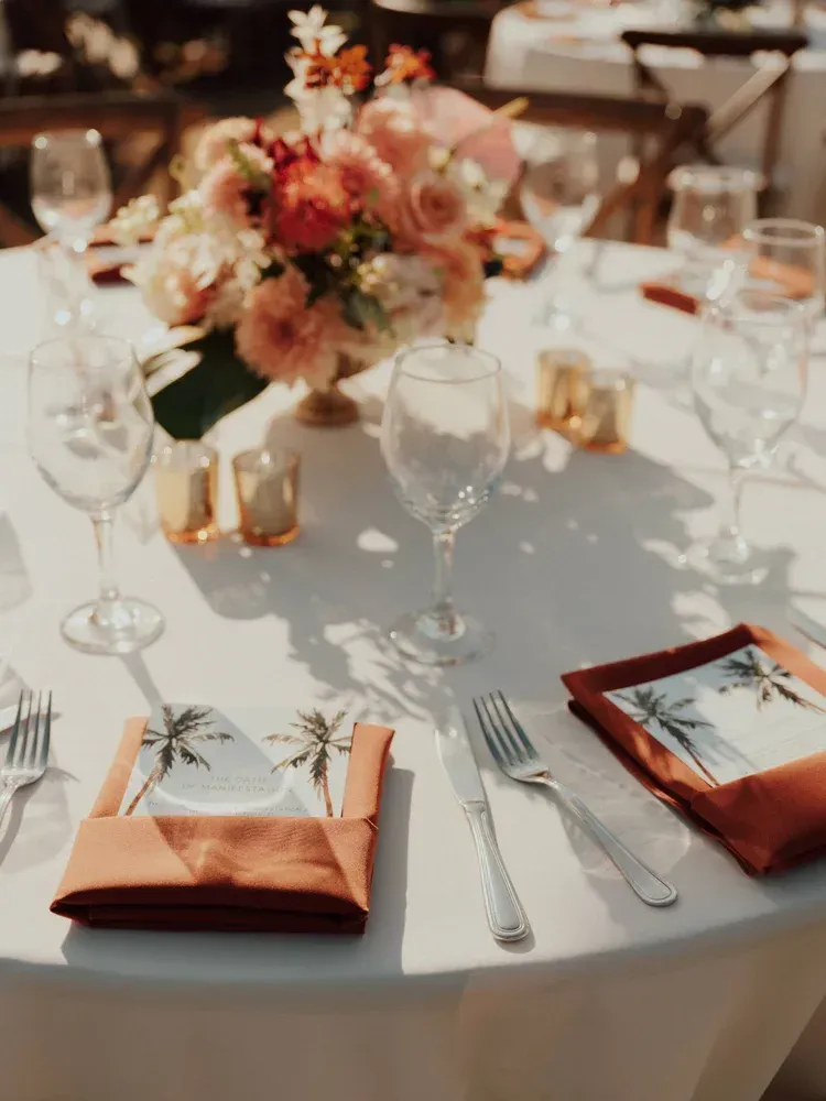 Elegant table setting with peach napkins, gold accents, and a floral centerpiece at a formal event