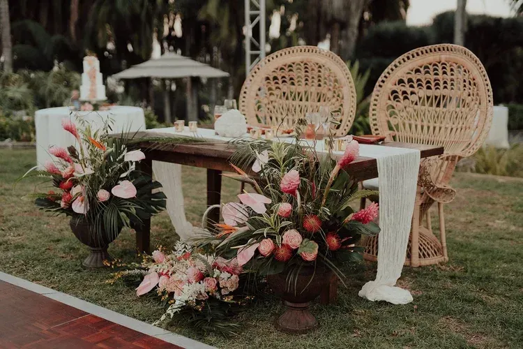 Floral wedding table with wicker chairs outdoors on a grassy lawn