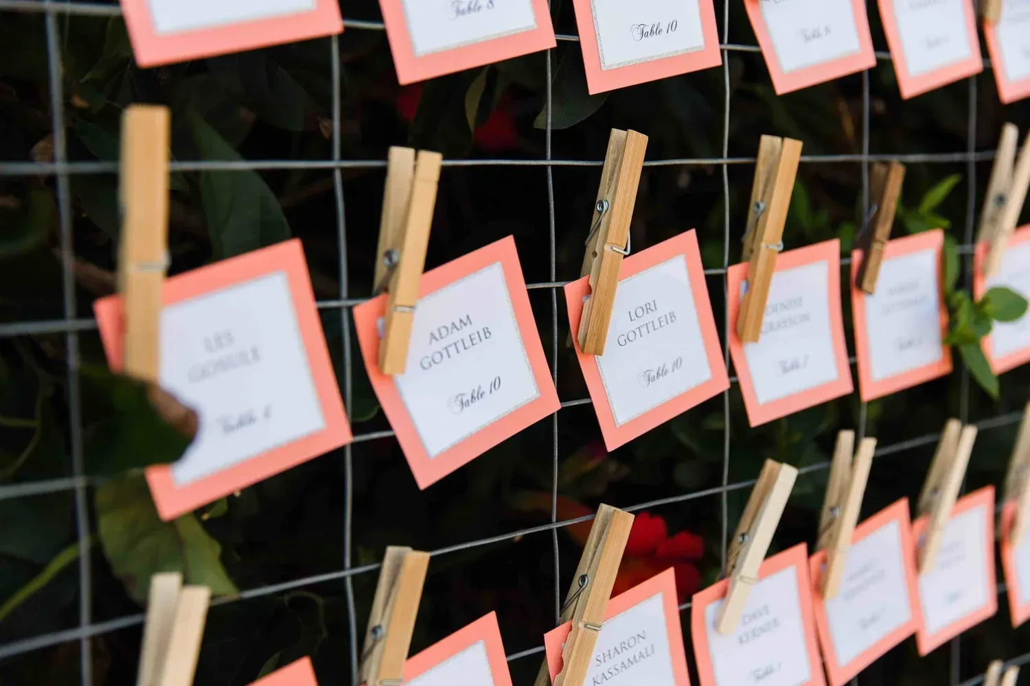 Small handwritten notes clipped to a wire grid with wooden clothespins, some on pink-bordered cards.