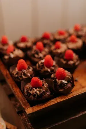 Chocolate cupcakes topped with raspberries on a wooden tray
