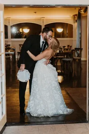 Bride and groom kissing at a warmly lit wedding venue entrance