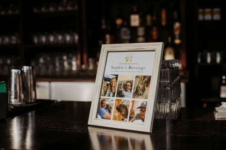 Framed collage on a bar counter with bottles and glassware in the background