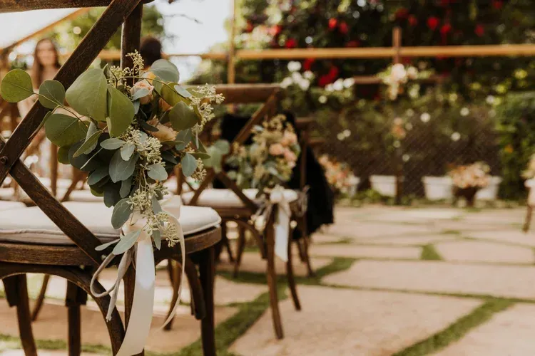 Floral-decorated wooden chairs along a stone path in an outdoor garden setting