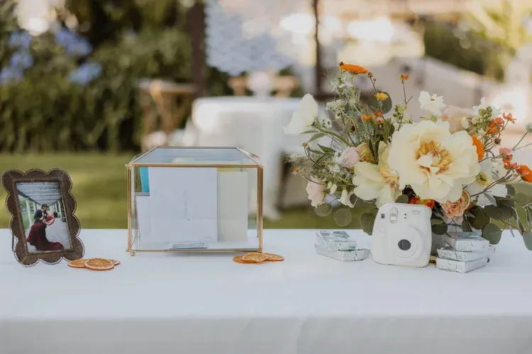 Wedding memory table with framed photo, glass card box, flowers, and white instant camera