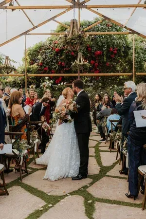 Bride and groom exchanging vows in a flower-filled greenhouse ceremony