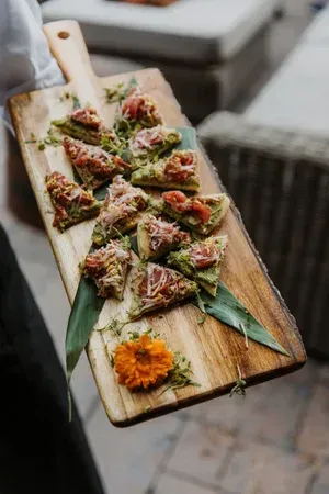 Wooden board with colorful appetizer bites and garnish on a rustic table