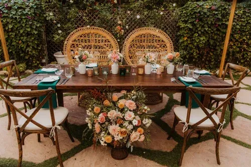 Elegant outdoor dining table with flowers, candles, and wicker chairs in a garden setting