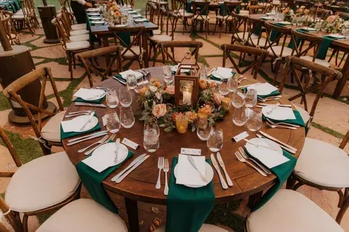 Round banquet tables set with white plates and teal napkins in an outdoor event space