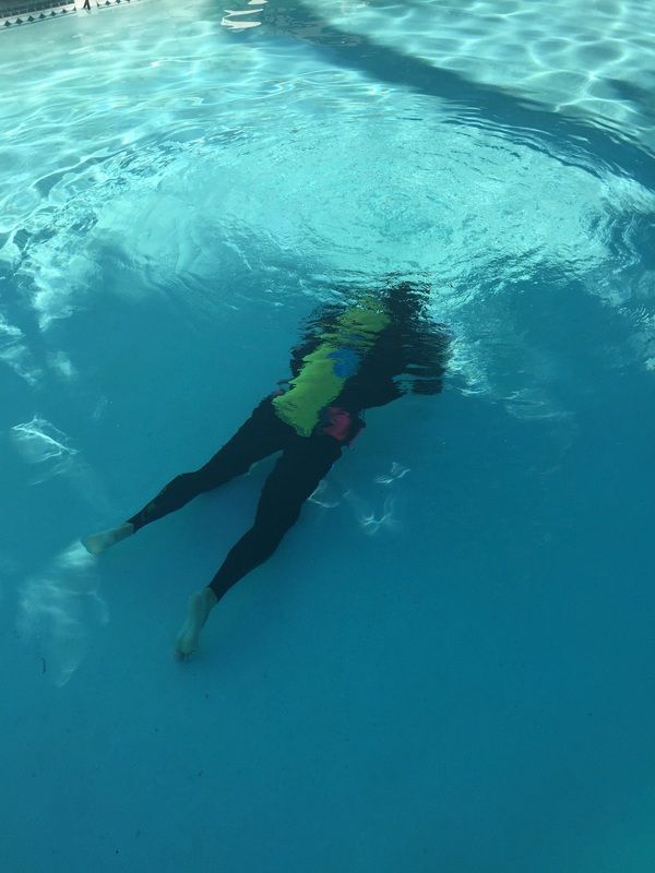 A person is swimming underwater in a swimming pool.