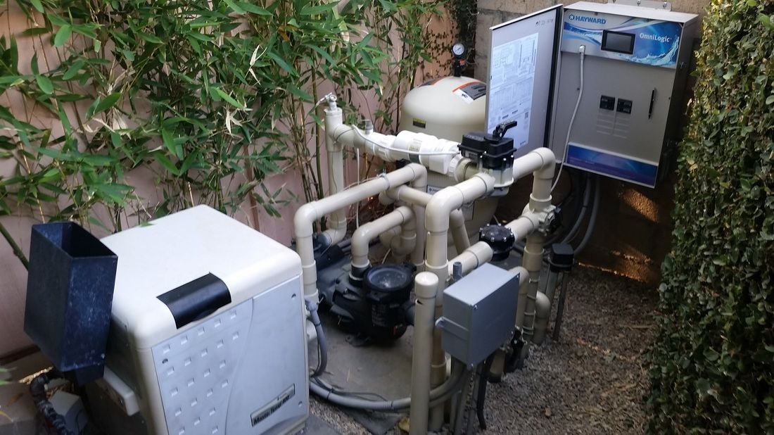 A swimming pool pump is sitting on the ground next to a fence.