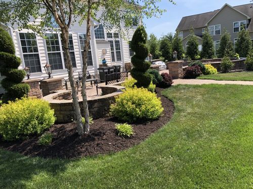 A Lush Green Lawn With Trees And Bushes In Front Of A House - Perry Hall, MD - Oakwood Landscaping LLC