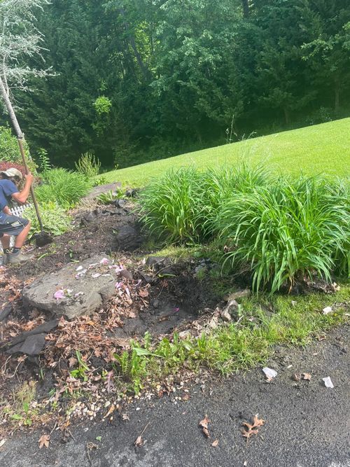 A Man Is Digging A Hole In The Ground Next To A Grassy Field - Perry Hall, MD - Oakwood Landscaping LLC