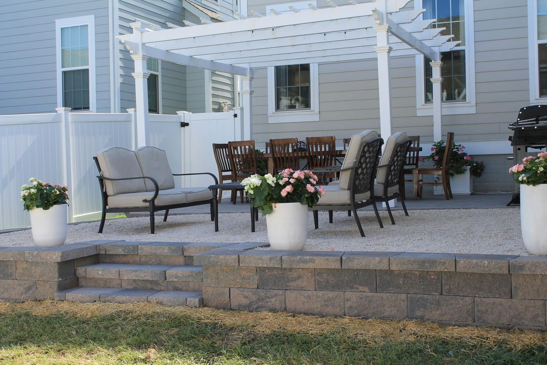 A Patio With A Pergola And Chairs In Front Of A House - Perry Hall, MD - Oakwood Landscaping LLC