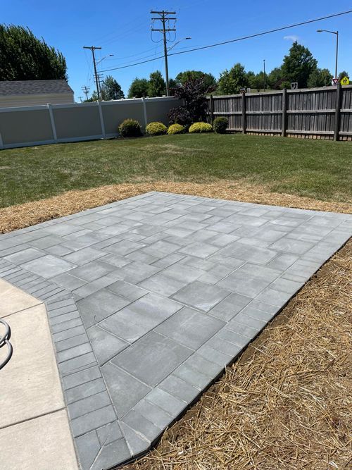 A Patio With A Fence In The Background Is Being Built In A Backyard - Perry Hall, MD - Oakwood Landscaping LLC