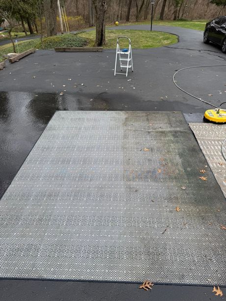 Outdoor driveway with a wet textured metal ramp and a parked car nearby