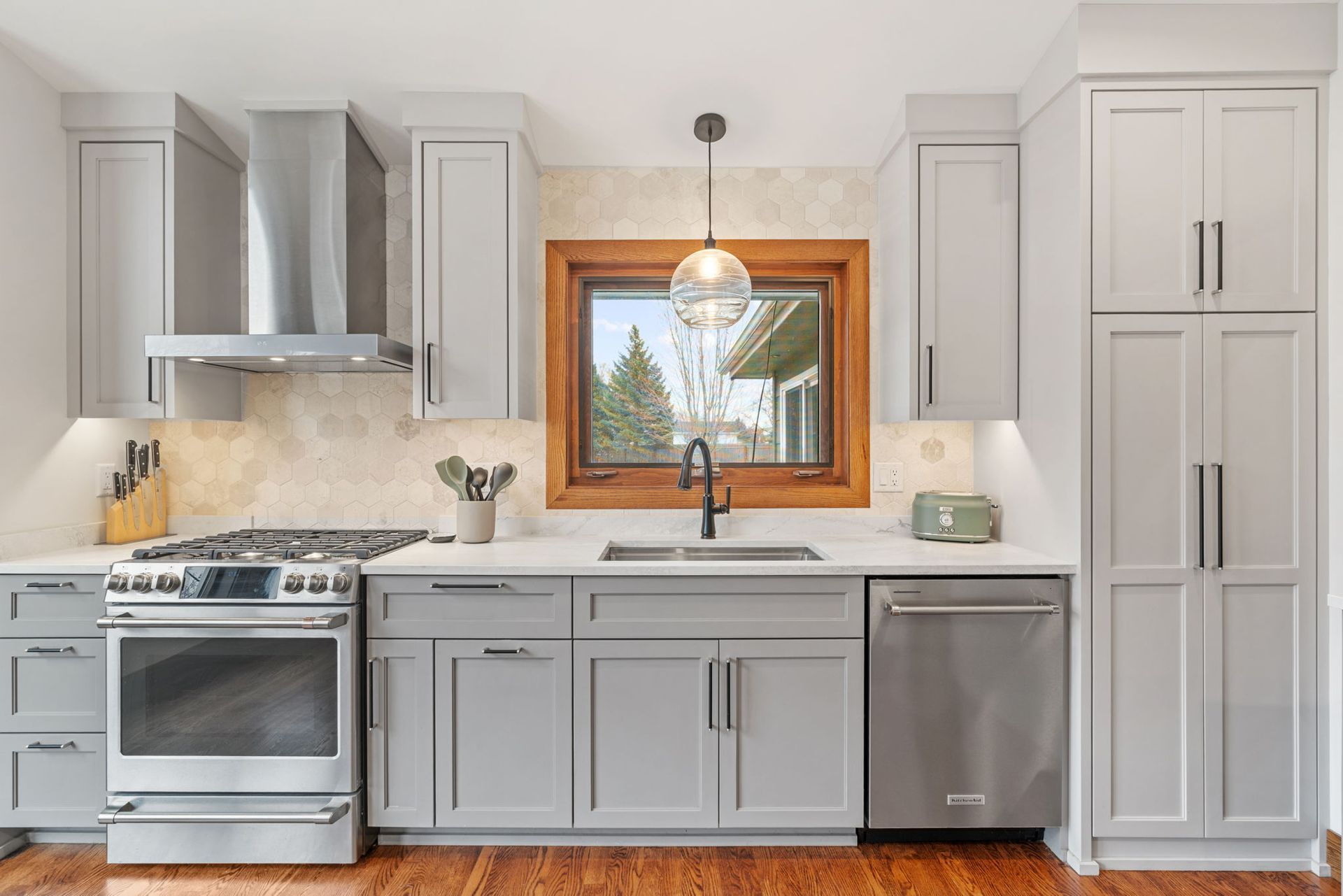 Modern kitchen with white cabinets, granite island, stainless appliances, and exposed brick accents