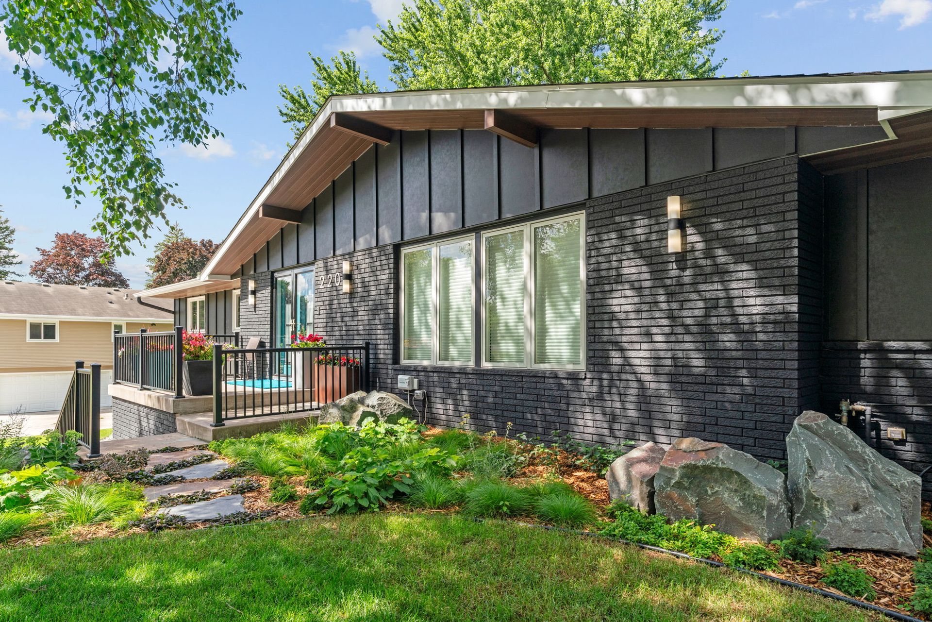 Warm wooden kitchen with stainless steel appliances, black granite island, and dining area beyond.