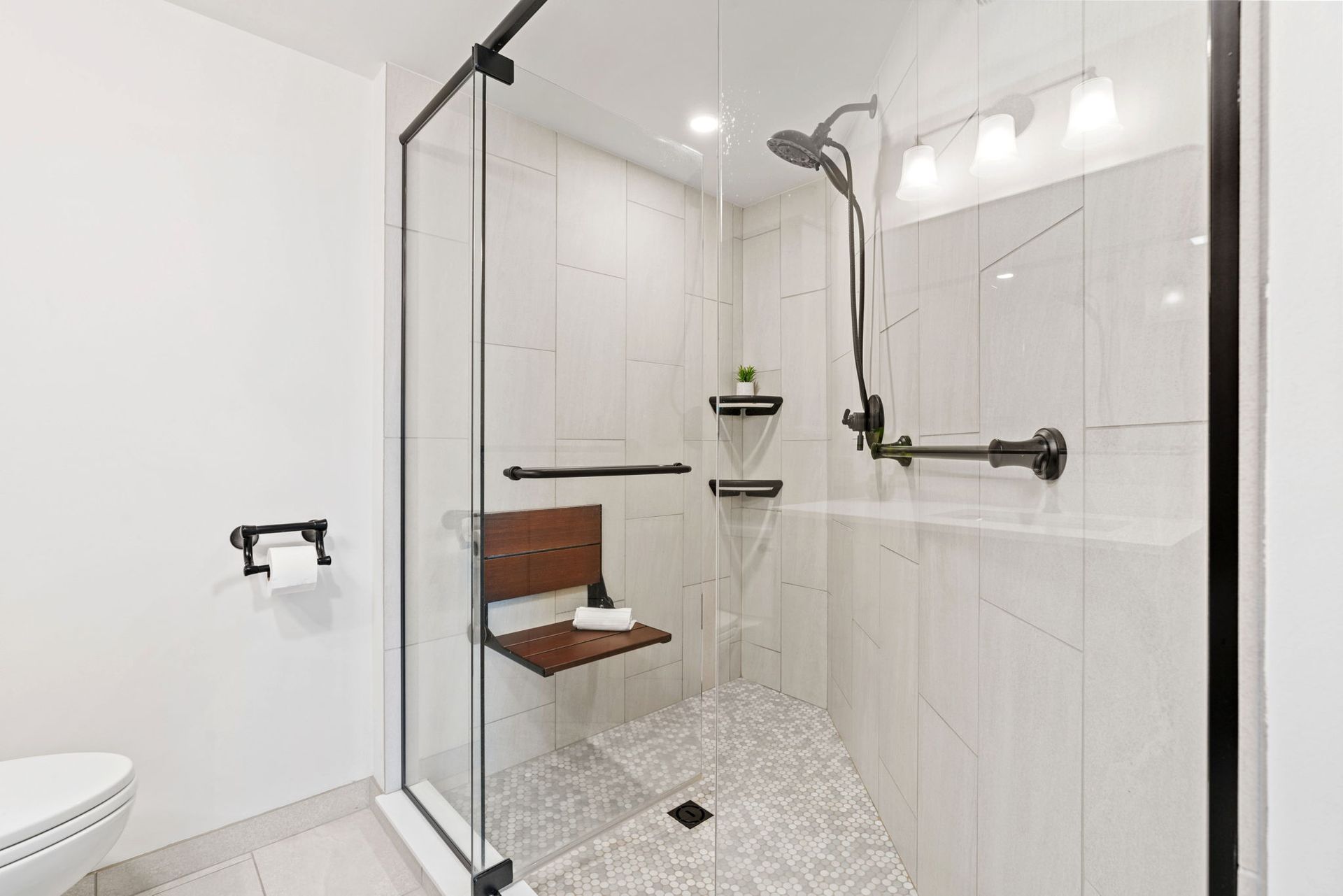 Modern bathroom with red walls, white vanity cabinets, large mirror, and dark wood floor