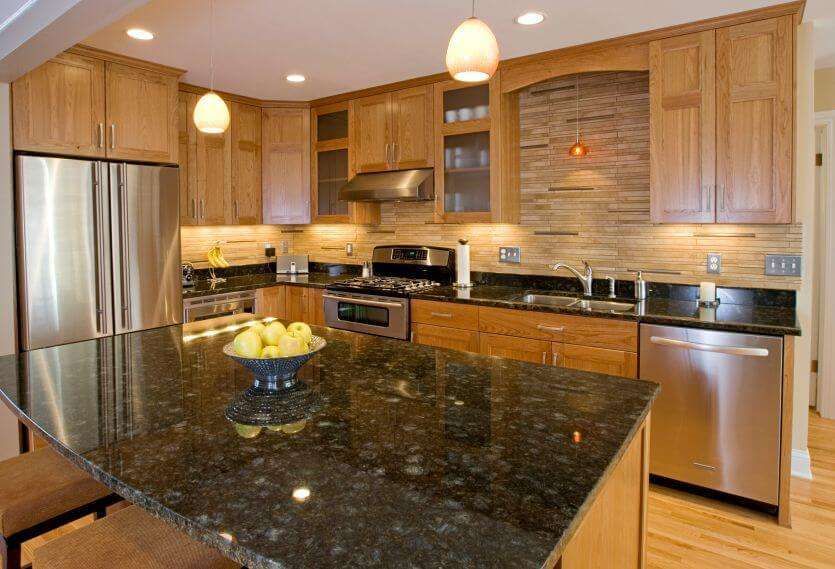 Modern kitchen with wood cabinets, black granite island, stainless steel appliances, and bowl of lemons
