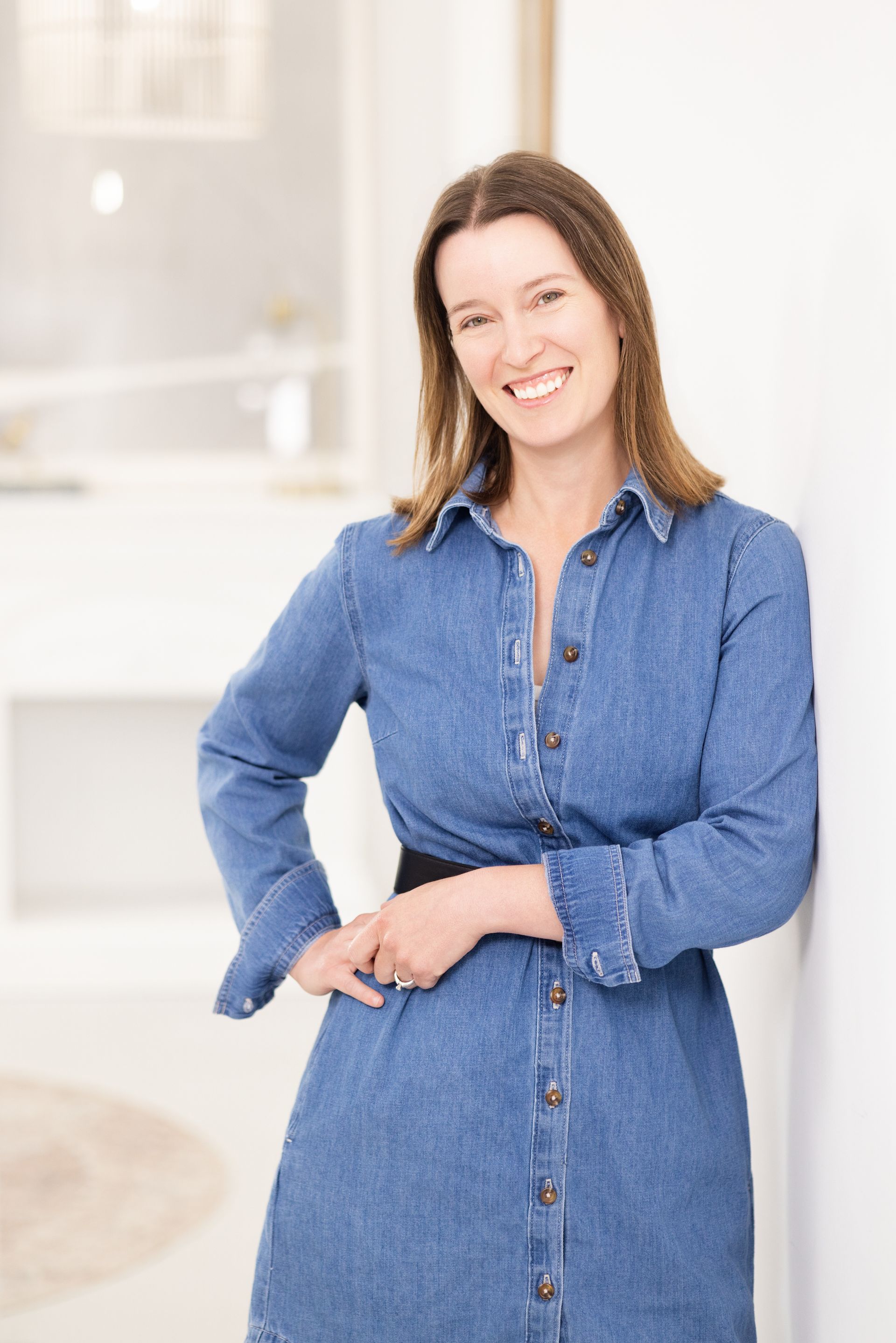 Smiling woman in a black top standing indoors by a bright window