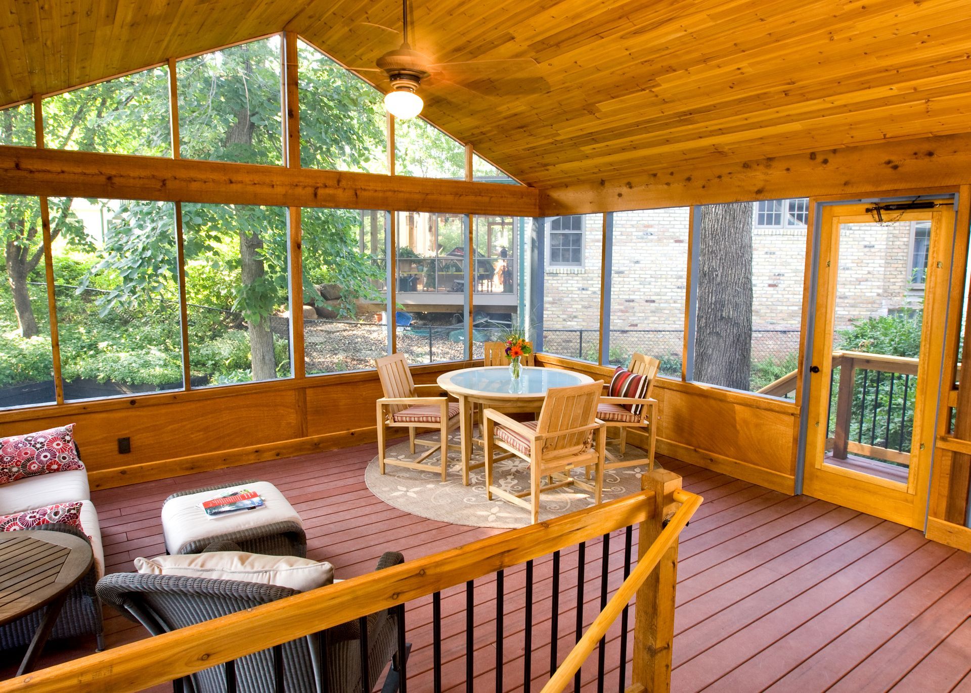 Blue-gray house with screened porch, red stairs, and tall trees in a leafy yard