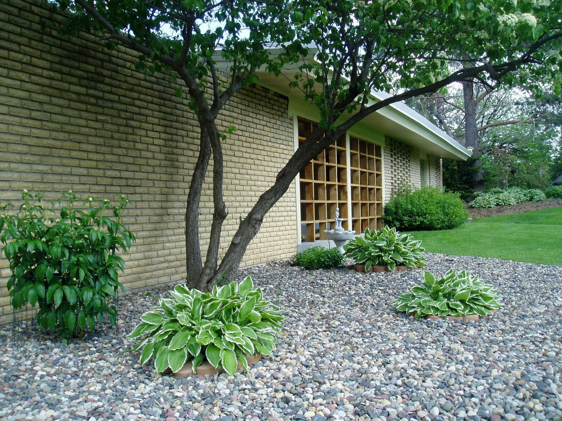 Driveway leading to a beige garage with a gate and landscaped entryway