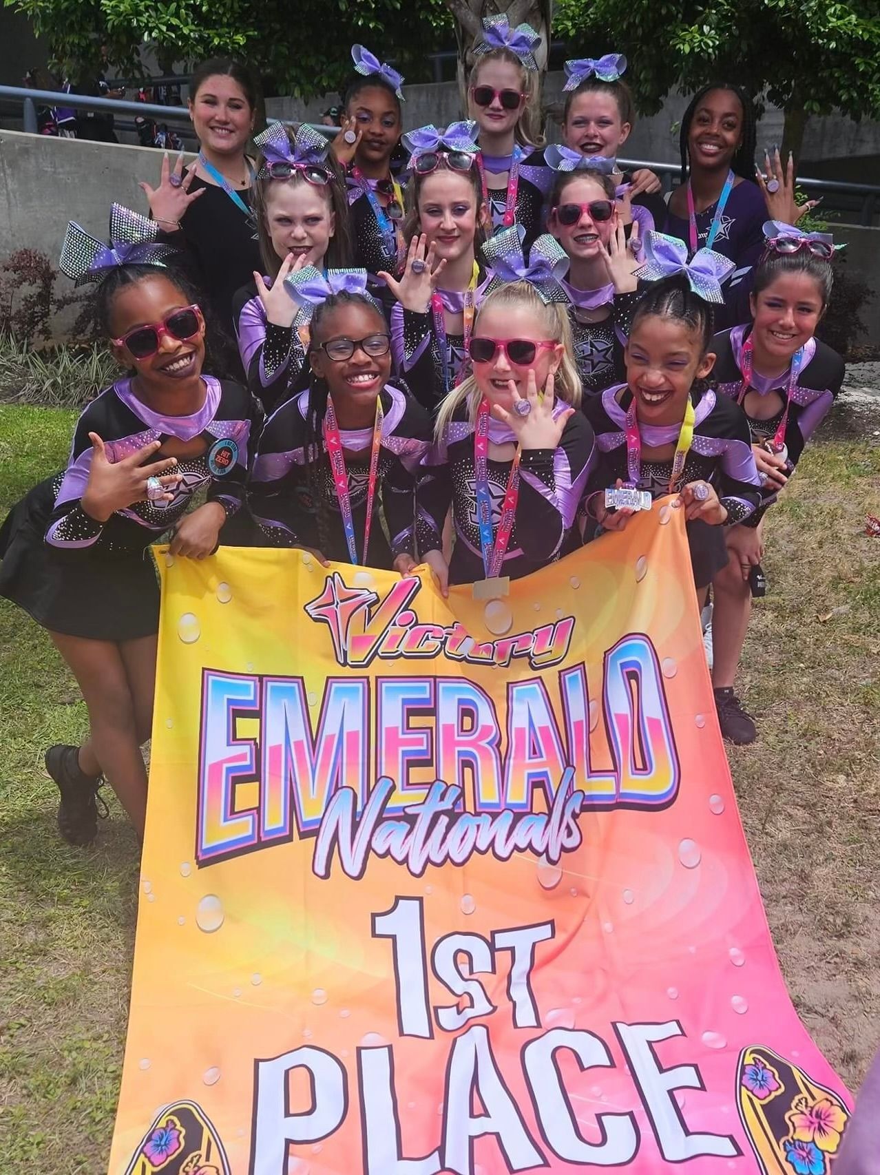 A group of cheerleaders are holding a banner that says emerald nationals 1st place.