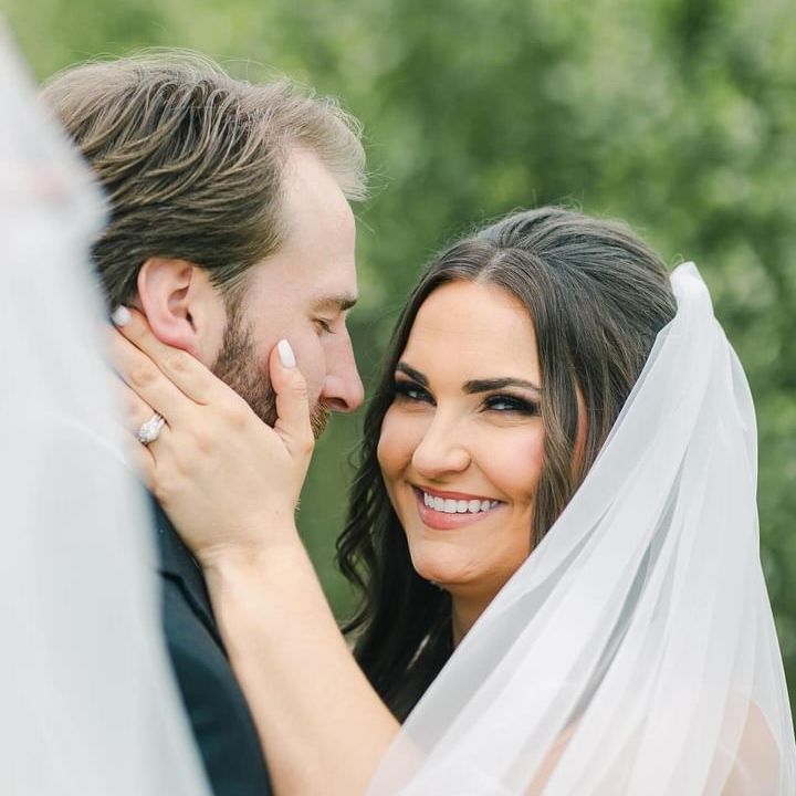 A bride and groom are looking at each other and smiling.