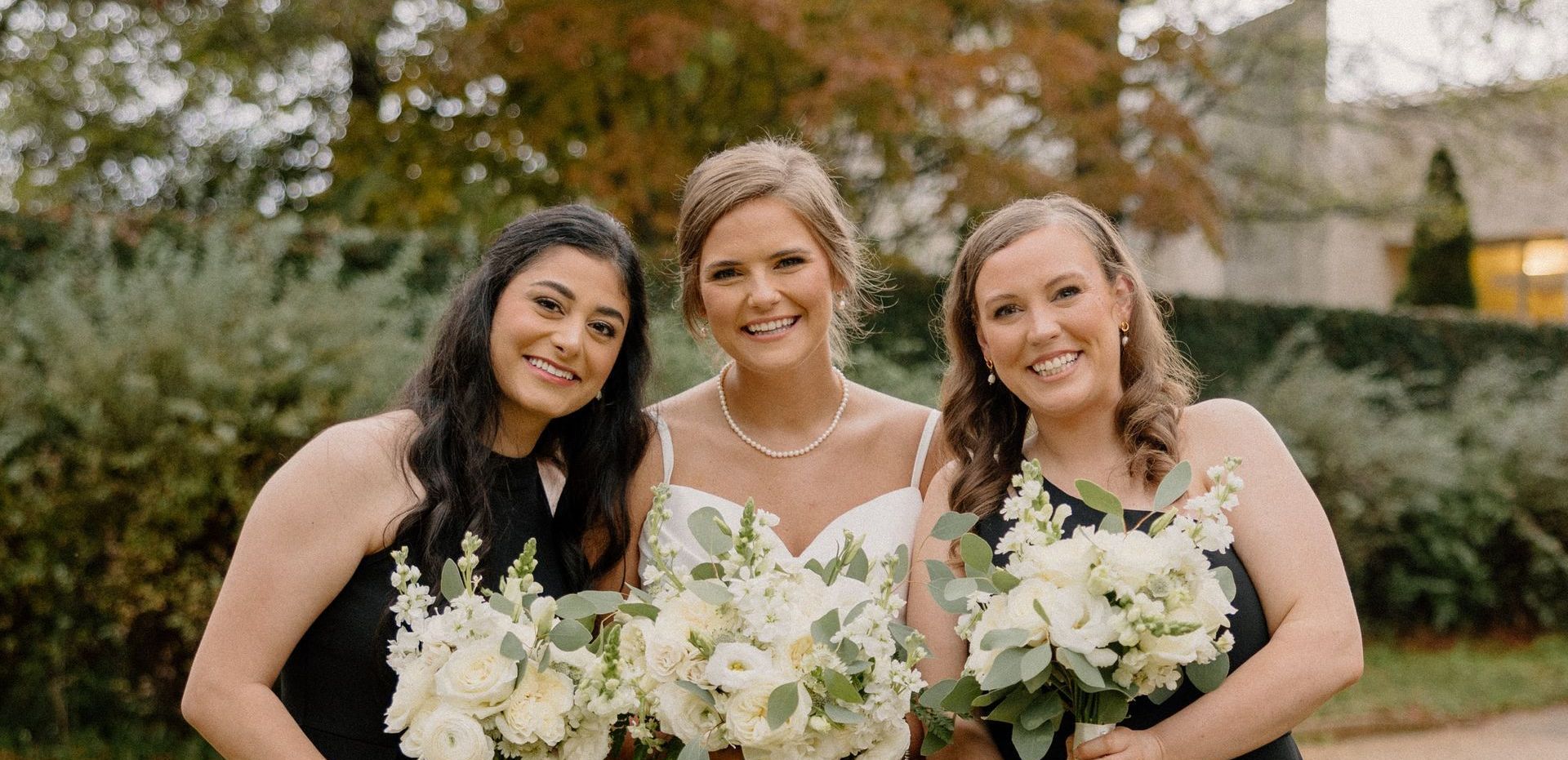 A bride and her bridesmaids are posing for a picture while holding bouquets of white flowers.