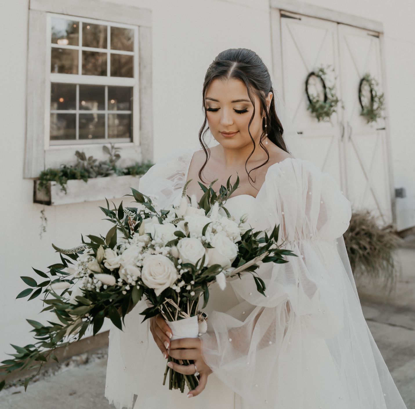 A bride in a white dress is holding a bouquet of white flowers.