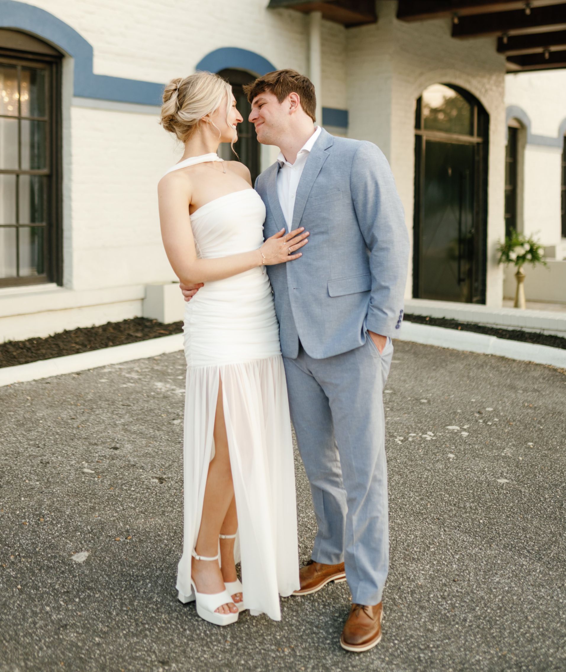 A bride and groom are posing for a picture in front of a building.