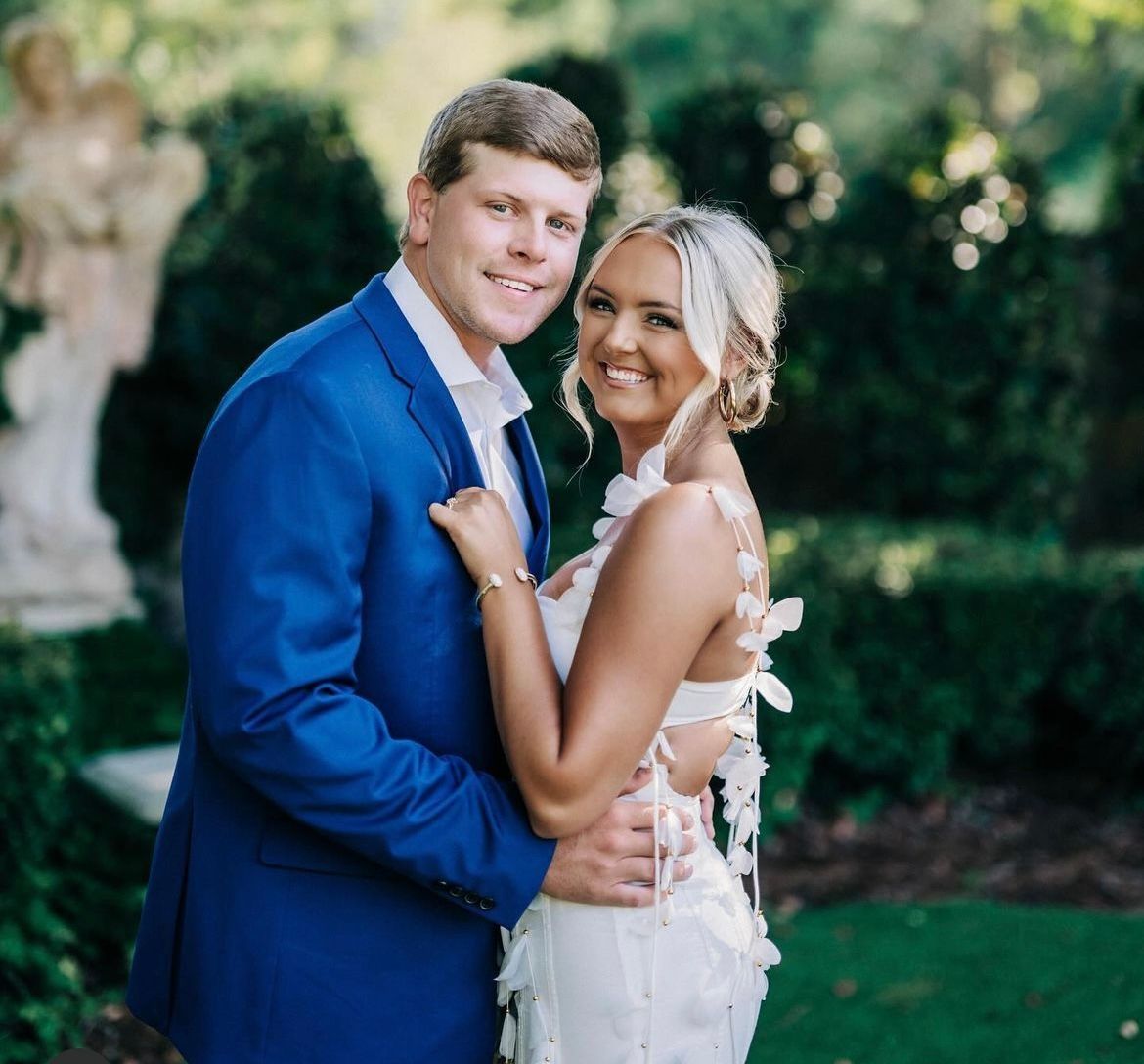 A bride and groom are posing for a picture in front of a statue.