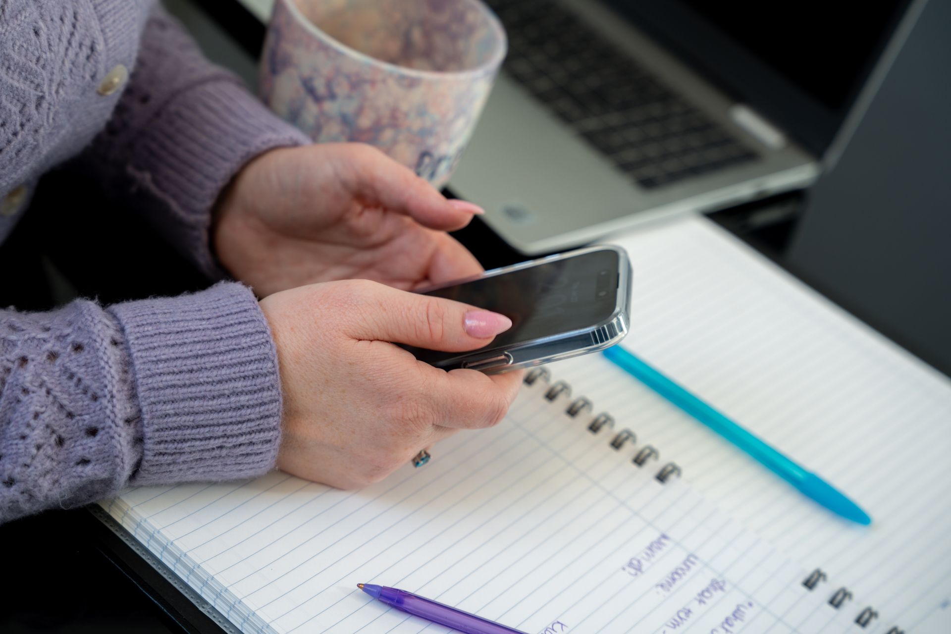Woman in green blazer at a table with papers, notebook, and phone.