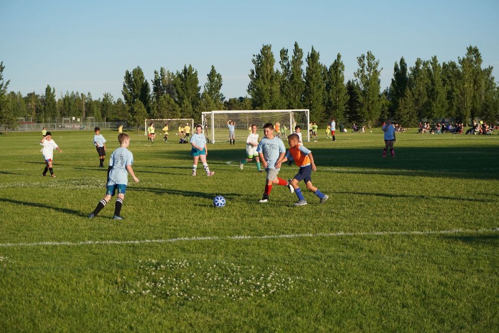 Kids  playing soccer in a park.