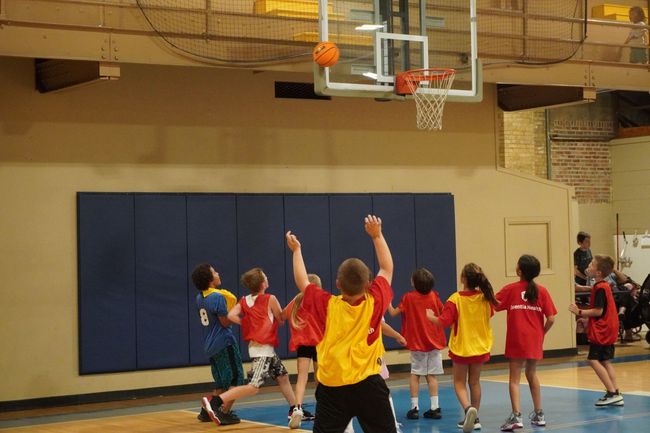 Kids playing basketball in a gym.