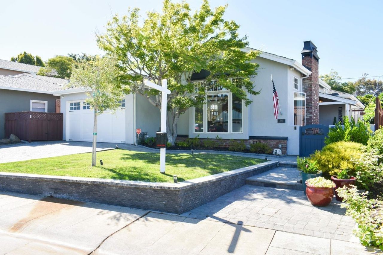 Suburban house with a white porch, green lawn, and an American flag by the front entrance